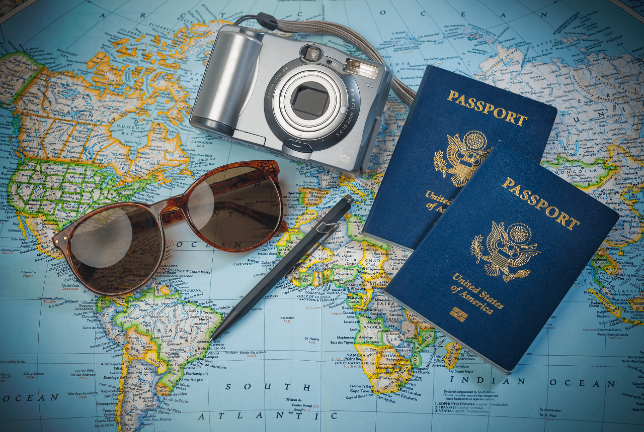 Passports for travel, camera and glasses on a map of the world. 
