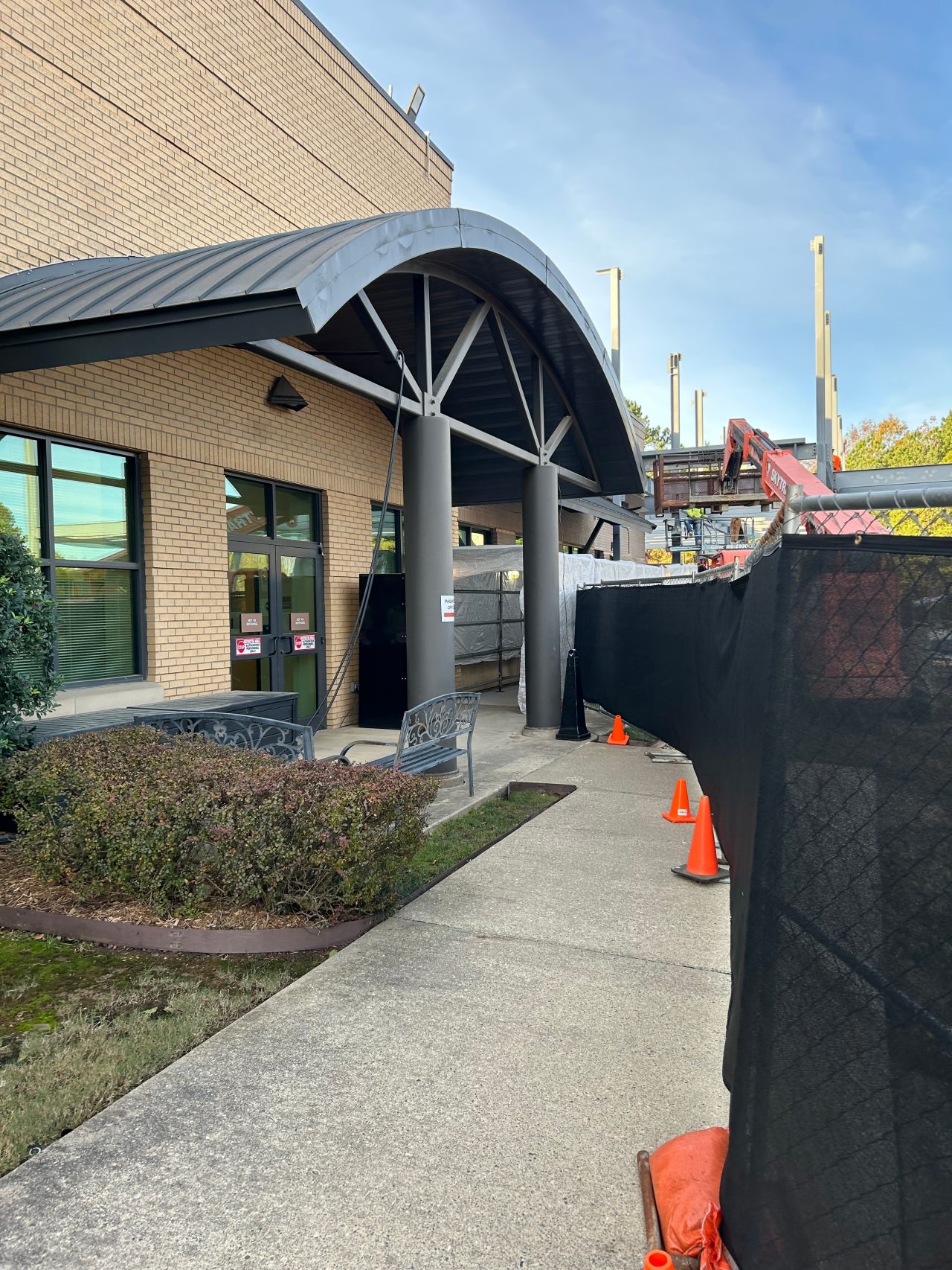 Front entrance of the Arkansas Passport Center. It is in a short tan brick building with constructions near the front entrance.